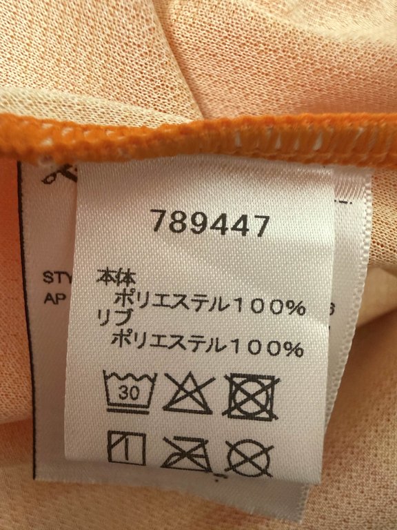 洗濯タグ側のラベル。数字6桁の品番が印字され、下にSTYLE NO.のラベルが覗いている